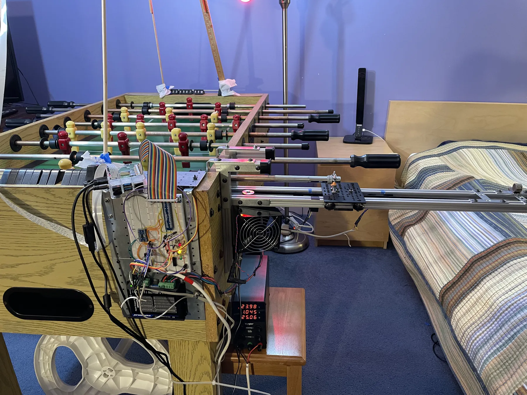 KURT fully mounted to the side of the table - electronics panel, stepper motor and a cooling fan - with the rail extending out past a bench power supply