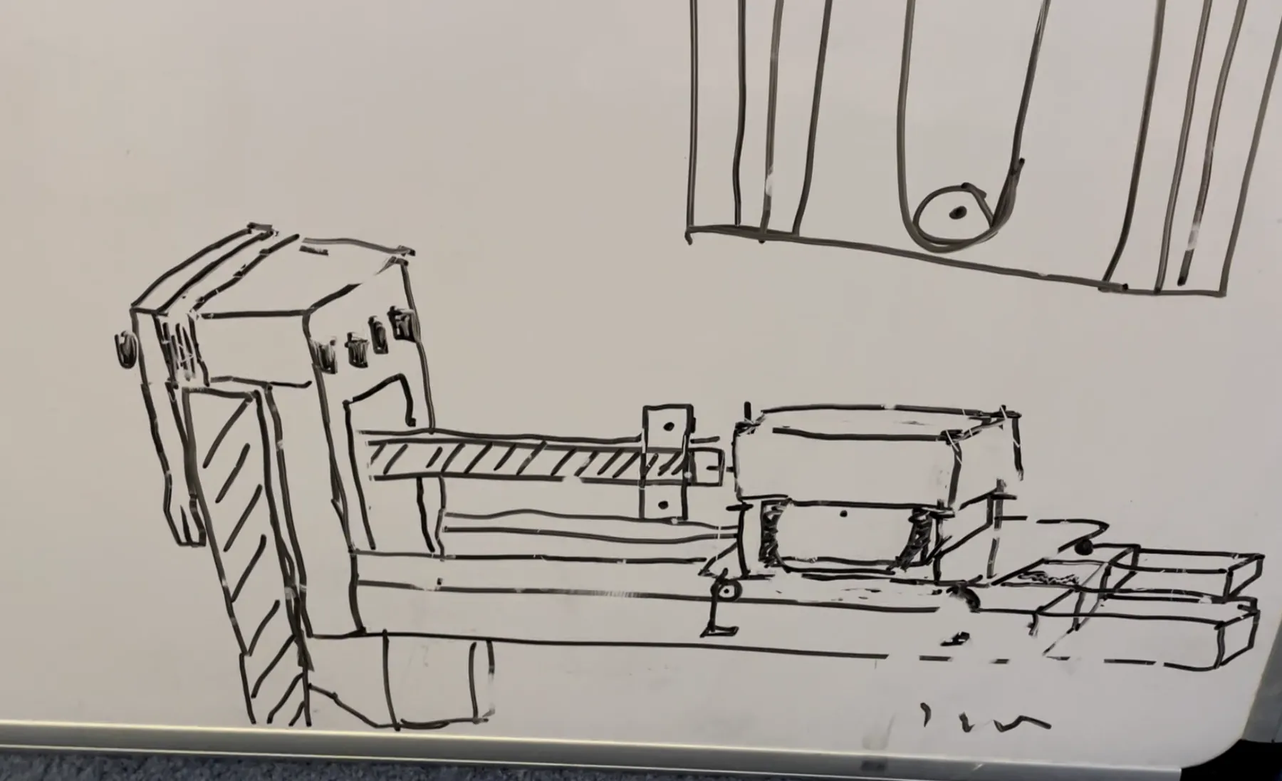 A whiteboard marker sketch of the drive mechanism - motor, rail and carriage clamped to the table - with a sketch of the goal end of the table above it